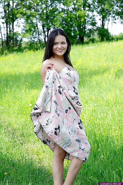 Nice Asian teen frees her breasts and pussy from her dress in a grassy meadow